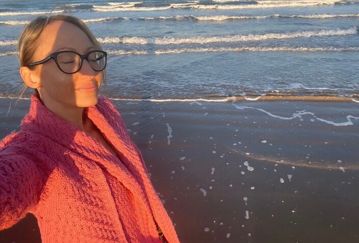 В коралловом кардигане на фоне морского заката